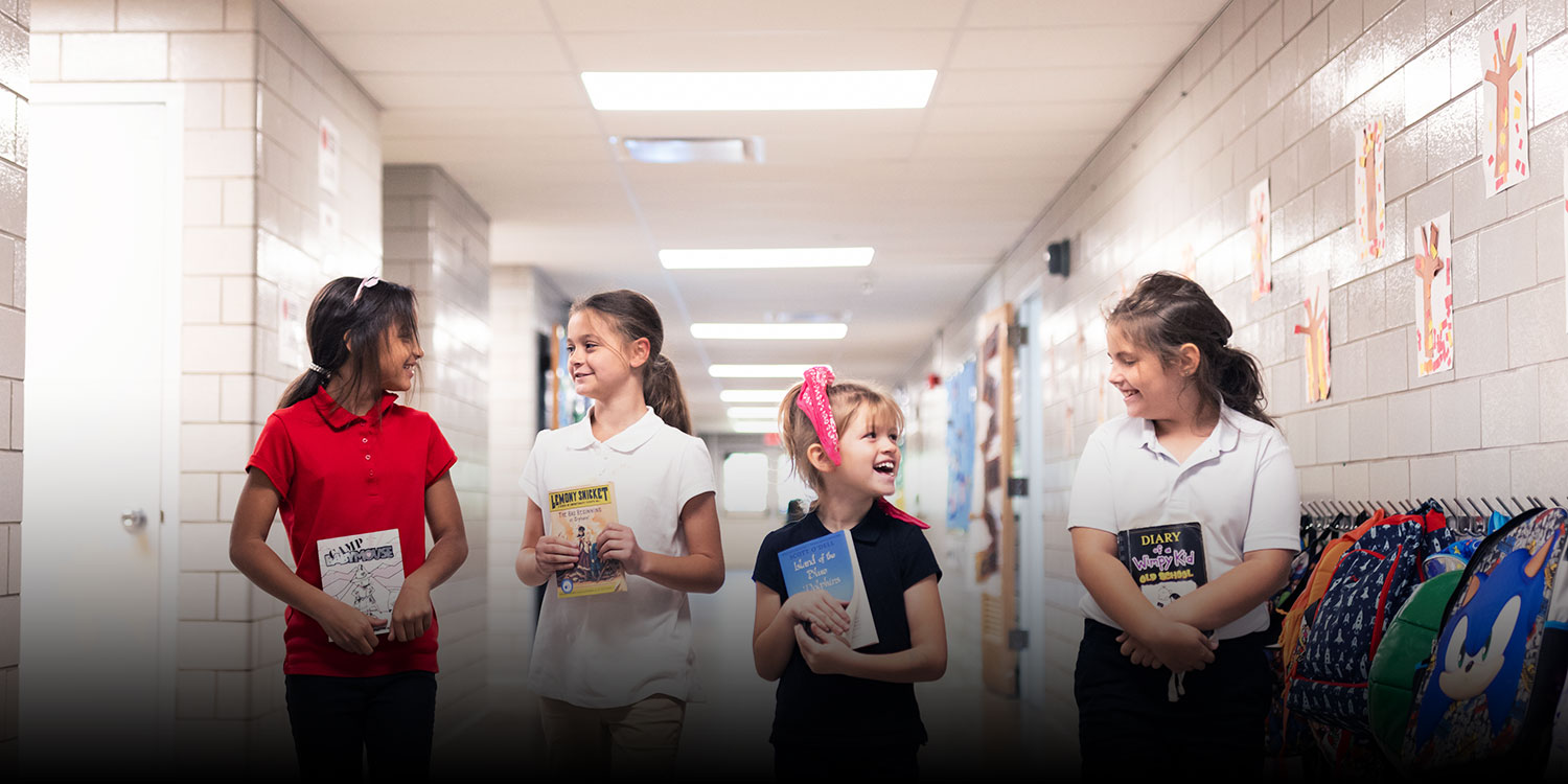 Students laughing and smiling together in school hallway.